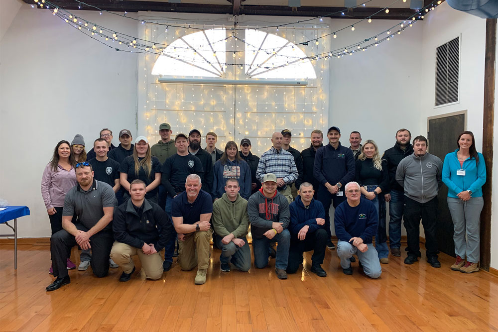 Group photo of two dozen crisis intervention team first responders in plain clothes posing in a conference room in 2021.