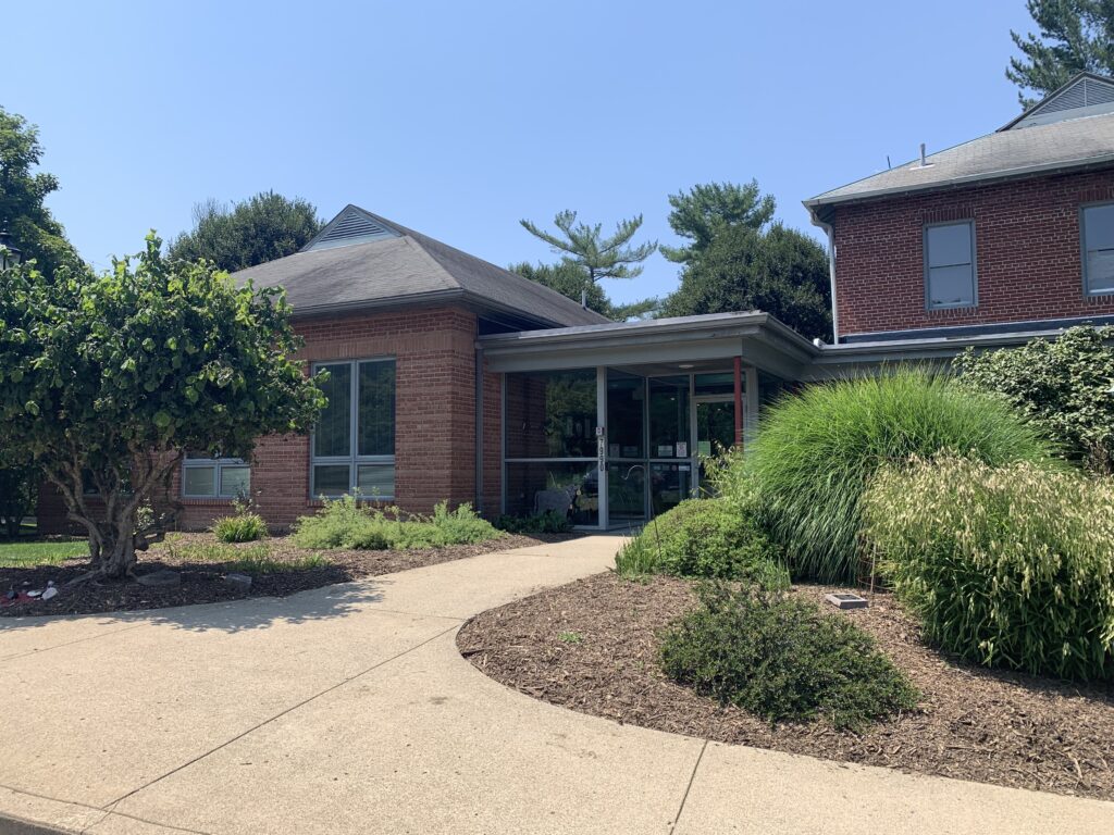 317 Board office building. Landscaped, concrete path leading to front door of brick building.